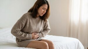 Woman feeling bloated and heavy looking at her stomach in the morning mirror